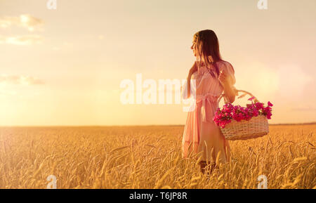 Jeune femme en champ de blé au coucher du soleil Banque D'Images