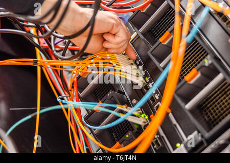 Il male Engineer de brancher un câble fibre optique à grande vitesse dans l'interrupteur de réseau Banque D'Images