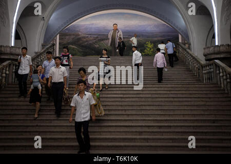 Les passagers sur le métro de Pyongyang à pied sous une grande fresque murale représentant Kim Il Sung. Banque D'Images