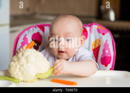 Bébé dans un siège pour enfant manger des légumes.bébé dans la chaise de bébé manger des légumes et souriant.comme premier aliment solide.enfant 8 mois Banque D'Images