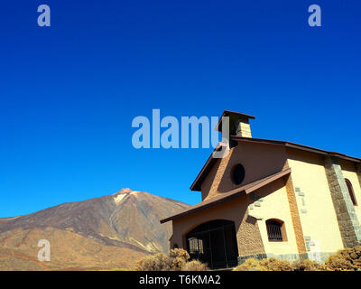 Une vieille église en pierre se dresse majestueusement au pied de la montagne Teide Tenerife sur en face de ciel ciel d'azur Banque D'Images