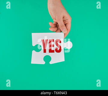 Big White puzzle dans la main sur un fond vert, l'inscription est oui Banque D'Images