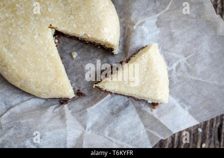 Des collations saines desserts sucrés. Aliments diététiques de remise en forme. Forme ronde halva sésame chocolat et coco combiné avec bouchon de remplissage sur la vieille planche de bois rustique. Veg Banque D'Images