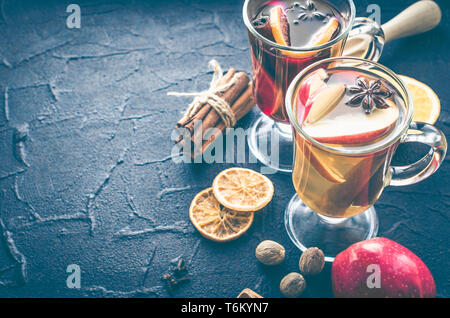 Deux verres de différents type de vin chaud ou de gluhwein basé sur les vins rouge et blanc avec des épices et ingrédients sur fond noir. Chaud épicé bever Banque D'Images