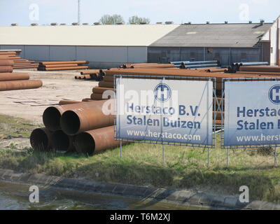 Canal, vue sur les tuyaux d'acier sur le site et les bannières publicitaires Herstaco.com, stockiste européen basé à Zeeland Banque D'Images