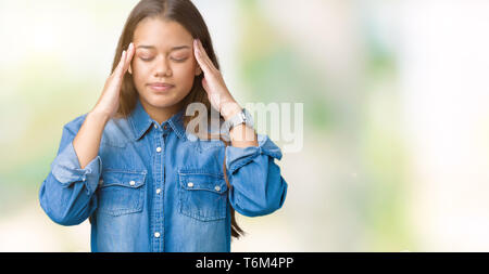 Jeune belle brunette woman wearing blue denim shirt sur fond isolé avec la main sur la tête pour la douleur dans la tête parce que le stress. Migraine souffrance Banque D'Images