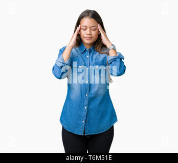 Jeune belle brunette woman wearing blue denim shirt sur fond isolé avec la main sur la tête pour la douleur dans la tête parce que le stress. Migraine souffrance Banque D'Images