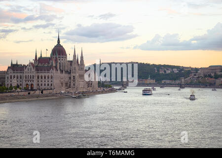 Le Parlement hongrois au coucher du soleil avec des bateaux de croisière le Danube. Banque D'Images