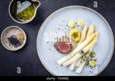 L'Allemand moderne sec barbecue de tranches de steak avec pommes de terre et asperges blanches sauce au beurre en vue de dessus comme sur une pla Banque D'Images
