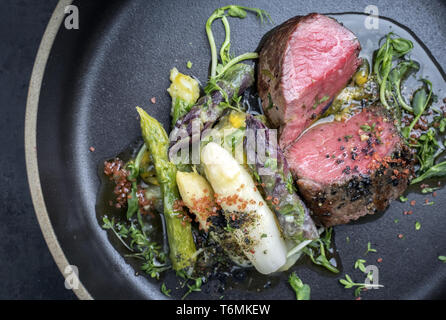 L'Allemand moderne Asperges Salade de pommes de terre et de tranches d'âge sec barbecue steak et herbes comme libre sur une plaque Banque D'Images