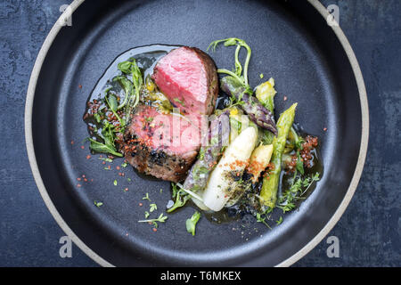 L'Allemand moderne Asperges Salade de pommes de terre et de tranches d'âge sec barbecue steak et herbes comme libre sur une plaque Banque D'Images