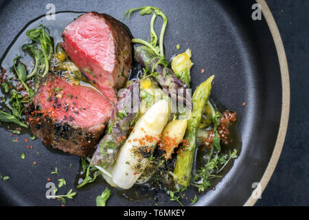L'Allemand moderne Asperges Salade de pommes de terre et de tranches d'âge sec barbecue steak et herbes comme libre sur une plaque Banque D'Images