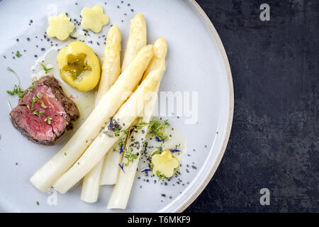L'Allemand moderne sec barbecue de tranches de steak avec pommes de terre et asperges blanches sauce au beurre en vue de dessus comme sur une pla Banque D'Images