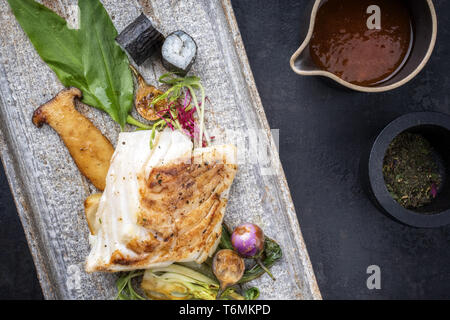 Morue frite japonaise moderne avec des filets de poisson bok choi et rouleaux de sushi en vue de dessus sur une plaque Banque D'Images