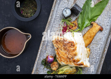 Morue frite japonaise moderne avec des filets de poisson bok choi et rouleaux de sushi en vue de dessus sur une plaque Banque D'Images