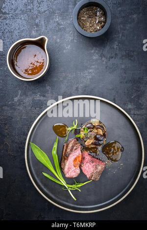 Barbecue traditionnel italien de tranches de steak à l'ail sauvage et pioppinos comme vue de dessus sur une plaque avec copie espace Banque D'Images