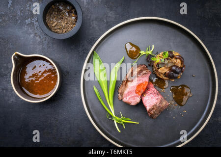 Barbecue traditionnel italien de tranches de steak à l'ail sauvage et pioppinos comme vue de dessus sur une plaque avec copie espace Banque D'Images