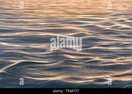 Close-up of soft vagues en mer au coucher du soleil, heure d'or abstract background. Banque D'Images