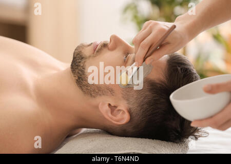 L'application de masque cosmétique Cosmetologist sur le visage de l'homme de spa salon Banque D'Images