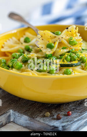 La plaque avec les pâtes, les courgettes et les pois verts. Banque D'Images