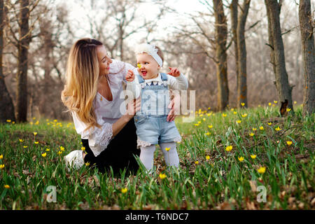 Montre enfant mère fleur plumés. Elle tient dans sa main une forêt tulip. Jeune famille en promenade dans la journée de printemps sur le pré. La Fête des mères. Mothe Banque D'Images