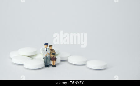 Couple de personnes âgées figure assis sur un tas de pilules blanches. Banque D'Images