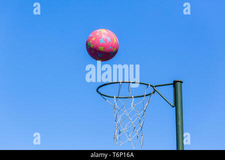 Le netball nasse avec une boule rouge en vol sur fond de ciel bleu . Banque D'Images