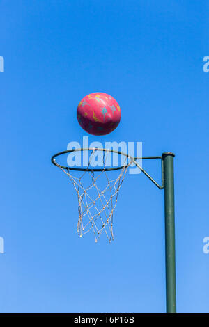 Le netball nasse avec une boule rouge en vol sur fond de ciel bleu . Banque D'Images