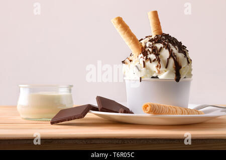 La crème et la crème glacée choco décoré de copeaux de chocolat et des gaufres sur une plaque sur une table en bois. Composition horizontale. Vue de face. Banque D'Images