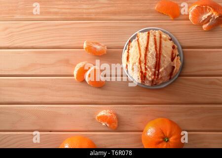 La crème glacée Mandarin tasse décorée avec des segments de mandarines sur une table en bois. Composition horizontale. Vue d'en haut. Banque D'Images