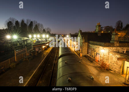 Vue nocturne à angle élevé de la gare de Bridgnorth rétro éclairée par une soirée froide et sombre. Les projecteurs montrent les locomotives à vapeur et diesel sur les voies de garage. Banque D'Images