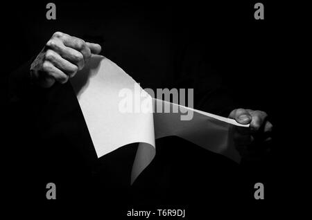 Un homme de déchirer un morceau de papier en noir et blanc. Banque D'Images