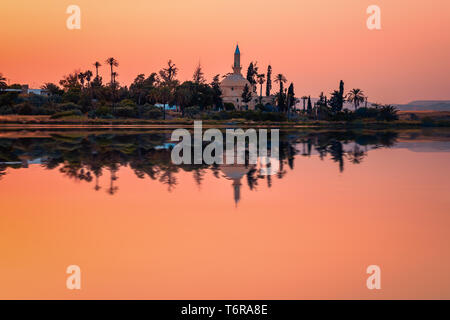 La vieille mosquée Hala Sultan Tekkes sur la rive du lac salé de Larnaca, Chypre au coucher du soleil Banque D'Images