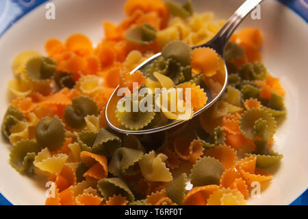 Close-up d'une assiette remplie d'un type de pâtes de différentes couleurs pour servir dans les salades d'été, dans l'image est non cuites Banque D'Images