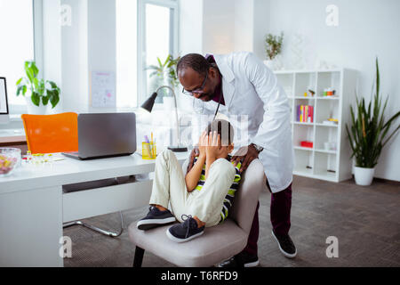 La peau sombre père travaillant comme médecin en regardant son fils mignon Banque D'Images