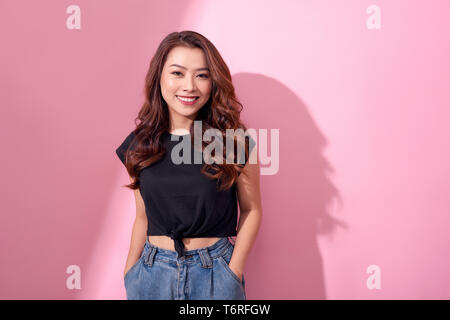 Beau portrait Asian young girl pose dans des vêtements décontractés avec sourire rayonnant isolés sur fond rose Banque D'Images