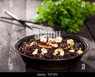 Riz noir cuit aux crevettes et légumes à plat sur un fond noir. Banque D'Images