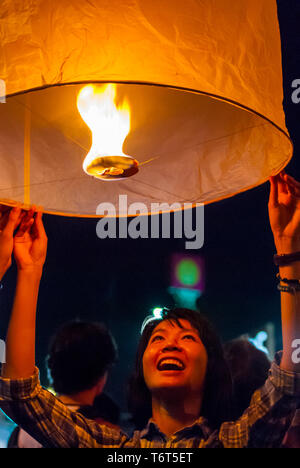 Chiang Mai, Thaïlande - 05 novembre 2015 : Une jeune femme de la foudre une lanterne pour la libérer au cours de Loy Krathong festival à Chiang Mai Banque D'Images