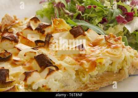 Une tranche de feta Quiche aux poireaux et fromage de chèvre ou sur une plaque avec feuille croustillant salade verte. La nourriture végétarienne en close up image. Banque D'Images