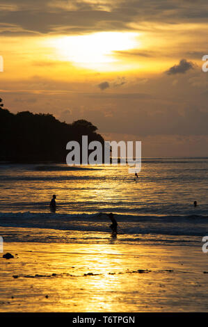 Les touristes pour le coucher du soleil sur la plage de Jimbaran, à Bali, Indonésie Banque D'Images