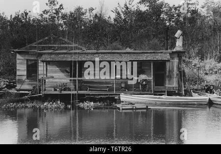 Photographie d'African American fisherman reposant sur la terrasse de sa maison le long du Bayou près de Akers, Louisiane, Octobre, 1938. À partir de la Bibliothèque publique de New York. () Banque D'Images