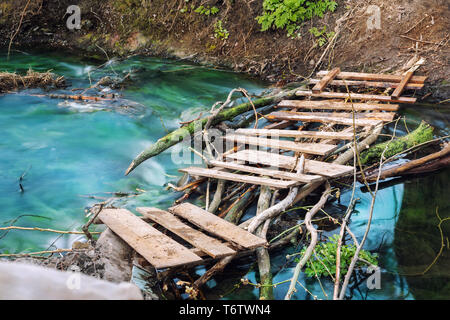 Sentier de randonnée dans la pittoresque vieille planche en bois pont sur ruisseau de montagne propre avec eau turquoise. Paysage naturel et paisible wit Banque D'Images