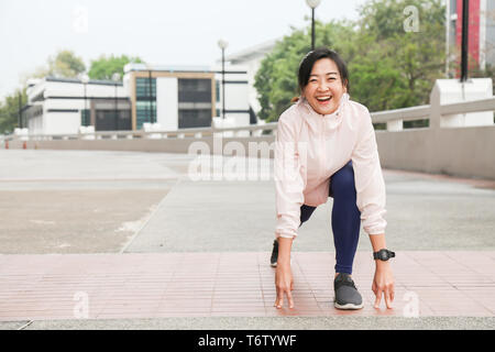 Une jeune femme asiatique et active runner est son point et soyez prêt pour courir dans un parc public Banque D'Images