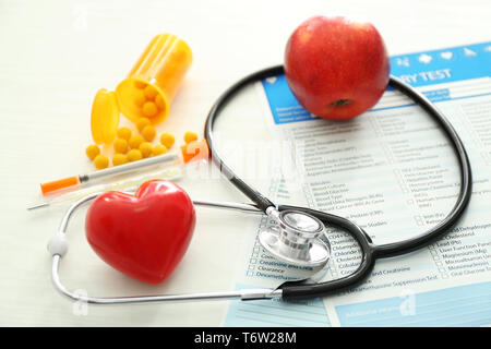 Stéthoscope avec coeur rouge et des listes de tests de laboratoire sur fond blanc. Concept de soins de santé Banque D'Images