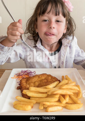 Peu d'Italien girl eating viande panées et frites Banque D'Images