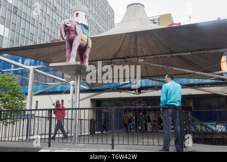 Les hommes sur le highwalk sous l'éléphant symbolique avec le dos-monté château à Elephant & Castle à Southwark, Londres du sud, le 29 avril 2019, à Londres, en Angleterre. Banque D'Images