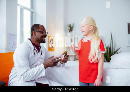 Blonde girl smiling en buvant du sirop contre la toux pédiatre visite Banque D'Images