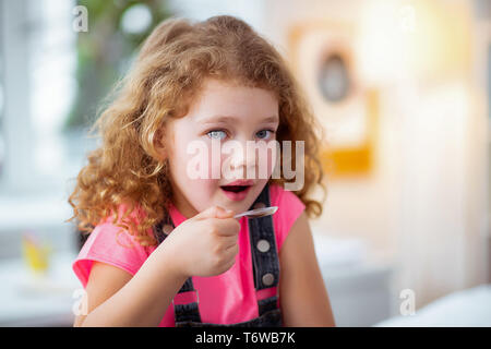 Belle fille d'ouvrir la bouche avant de prendre du sirop contre la toux Banque D'Images