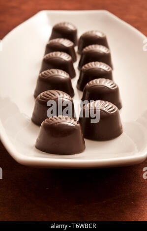 Bonbons de chocolat Pralines ou sur une assiette de porcelaine blanche Banque D'Images