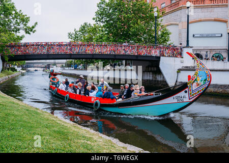 Aveiro, Portugal - 29 Avril 2019 : bateau traditionnel, les touristes de passage, le transport Moliceiro sous le pont couvert de confettis sur canal à Aveiro Banque D'Images